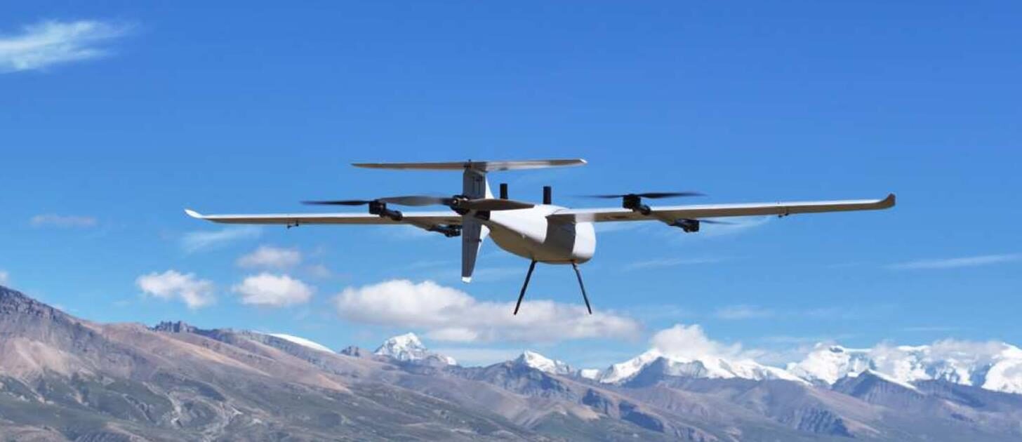SA240 Pro hovering on its lift rotors in front of a snow-capped mountain range